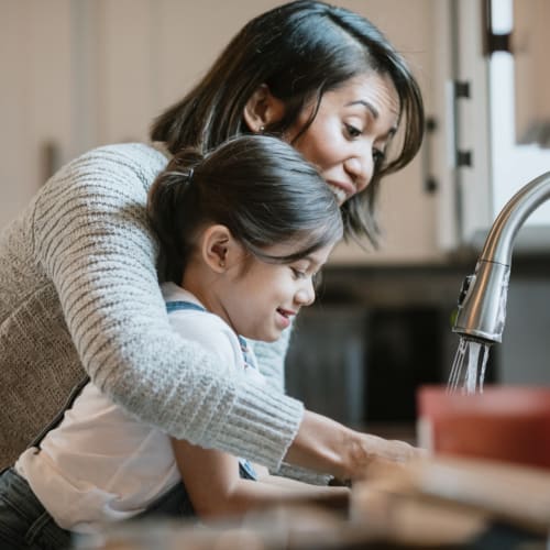 A residnet and daughter washing their hands in their kitchen Columbia Colony in Patuxent River, Maryland