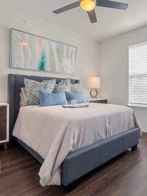 Elegant model master bedroom with hardwood style flooring and a ceiling fan at Auberge of Burleson in Burleson, Texas