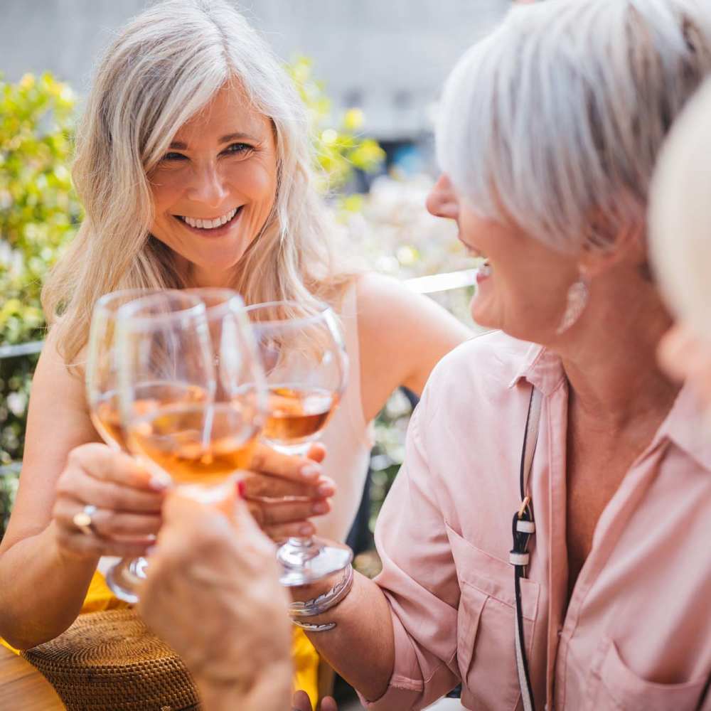 Two women toasting with glasses of rosé, smiling and enjoying a sunny outdoor gathering at Westwood Bluffs in Fresno, California