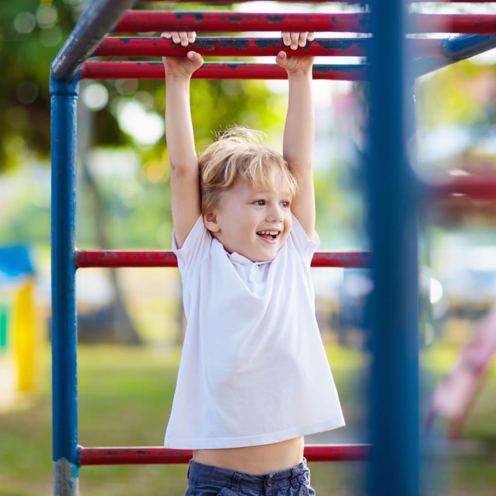 Child hanging from the monkey bars at the onsite children's playground at Mills Creek in Gastonia, North Carolina