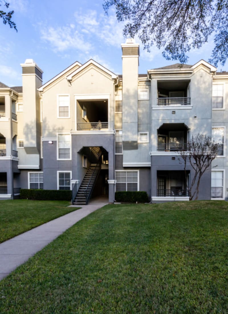 Unit entrance surrounded by green landscaping at Marquis at Stonegate in Fort Worth, Texas