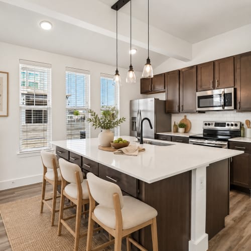 Open concept model living room and kitchen with faux wood flooring at Elevate at Skyline in McKinney, Texas