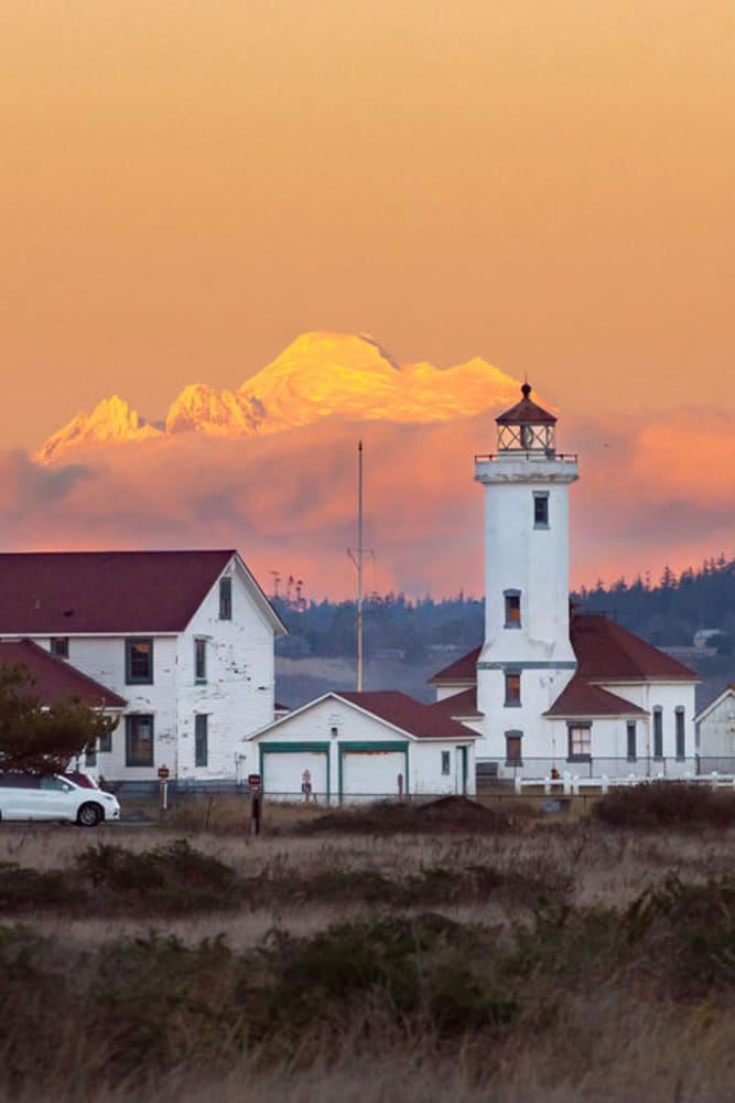 View of mountains behind a lighthouse near Admiralty Apartments in Port Townsend, Washington