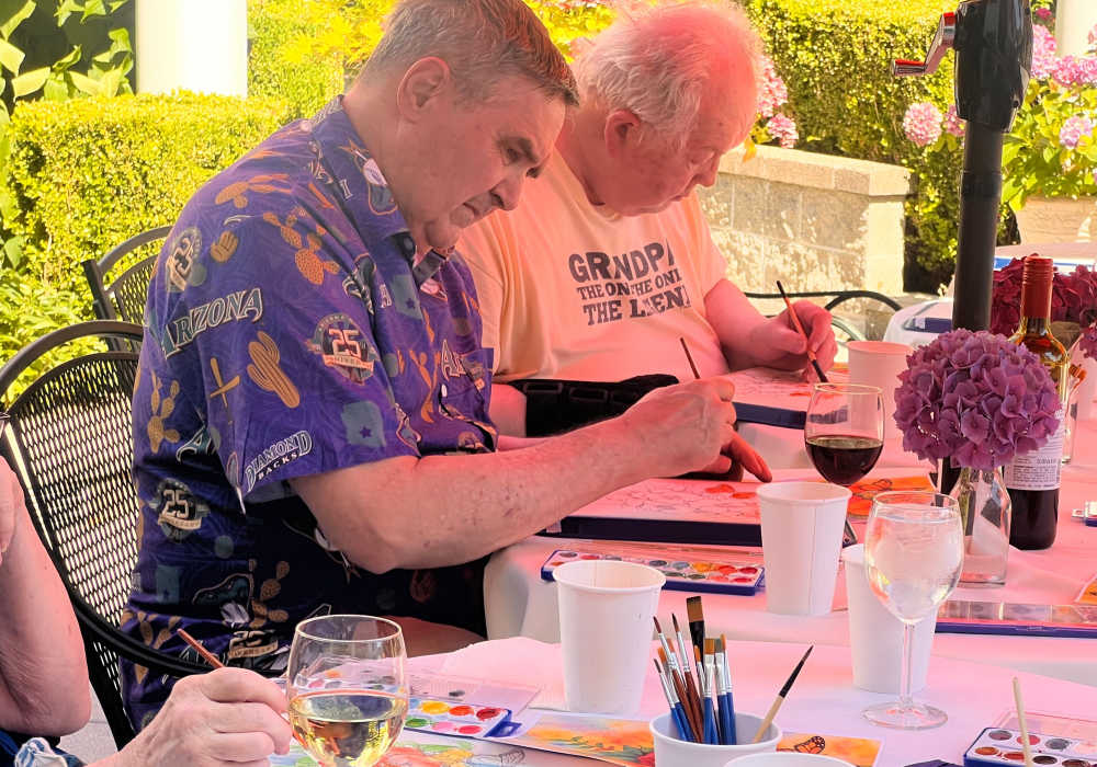 Residents having fun painting outdoors at Merrill Gardens at The University in Seattle, Washington