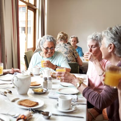 Residents sitting in a sunlit cafe eating breakfast at Arbor Glen Senior Living in Lake Elmo, Minnesota