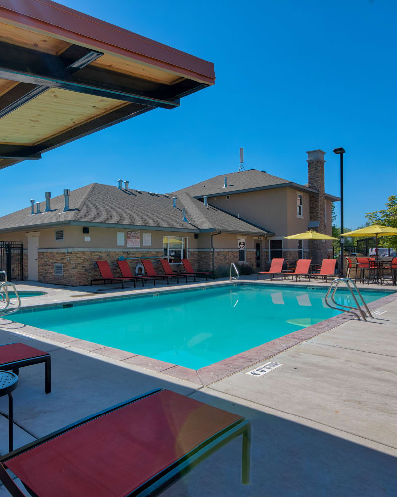 Shaded chaise lounge chairs next to the swimming pool at Meadowbrook Station Apartments in Salt Lake City, Utah