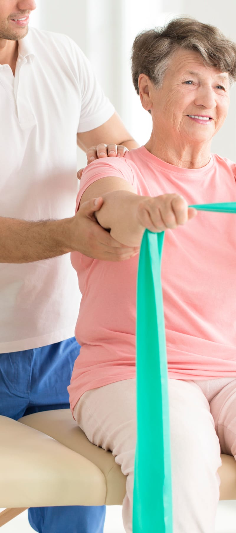 Resident working on strength training with a resistance band and a trainers assistance at Fair Oaks Health Care Center in Crystal Lake, Illinois