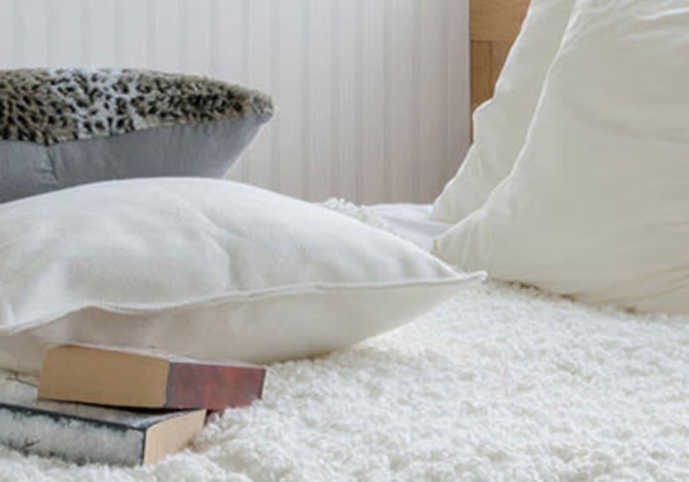 Close-up of bed with very soft blanket, lots of pillows and two reading books placed on top at Everwood at The Avenue in Murfreesboro, Tennessee