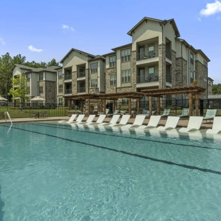 Sparkling swimming pool with sundeck lounge chairs at Auberge of Tyler in Tyler, Texas