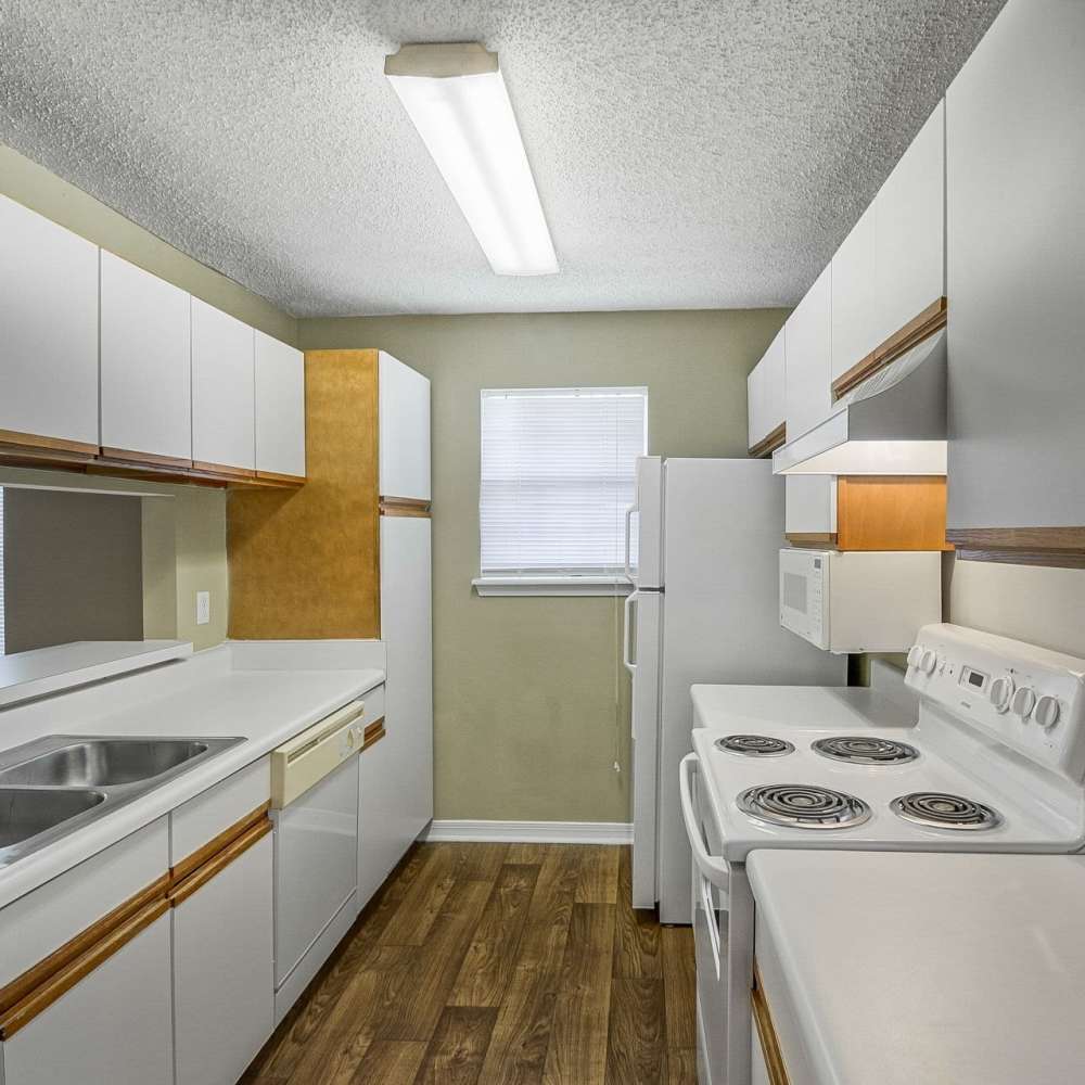 Cozy kitchen with all-white appliances and wood-style flooring at Royal Gulf Apartments in Biloxi,Mississippi