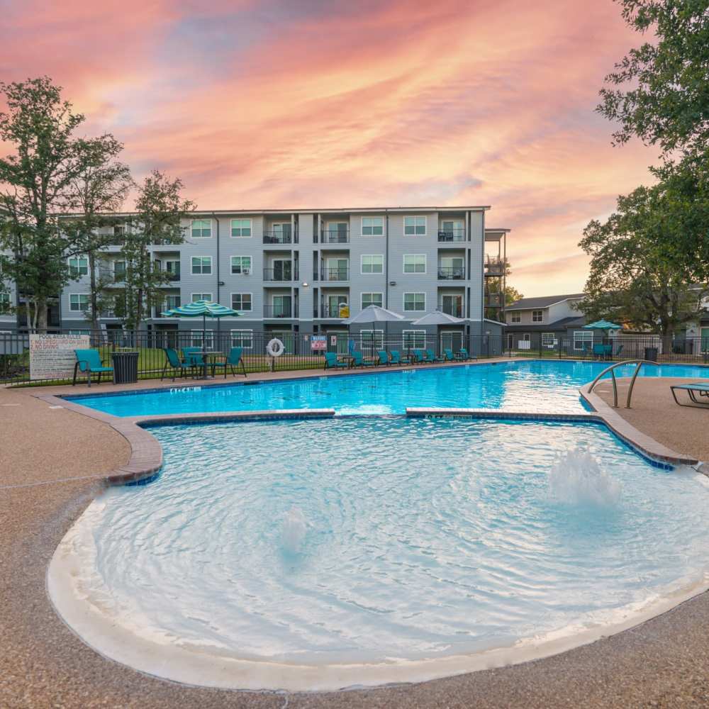 Sunset view of the apartments with the swimming pool at Regency Gardens in Bryan, Texas