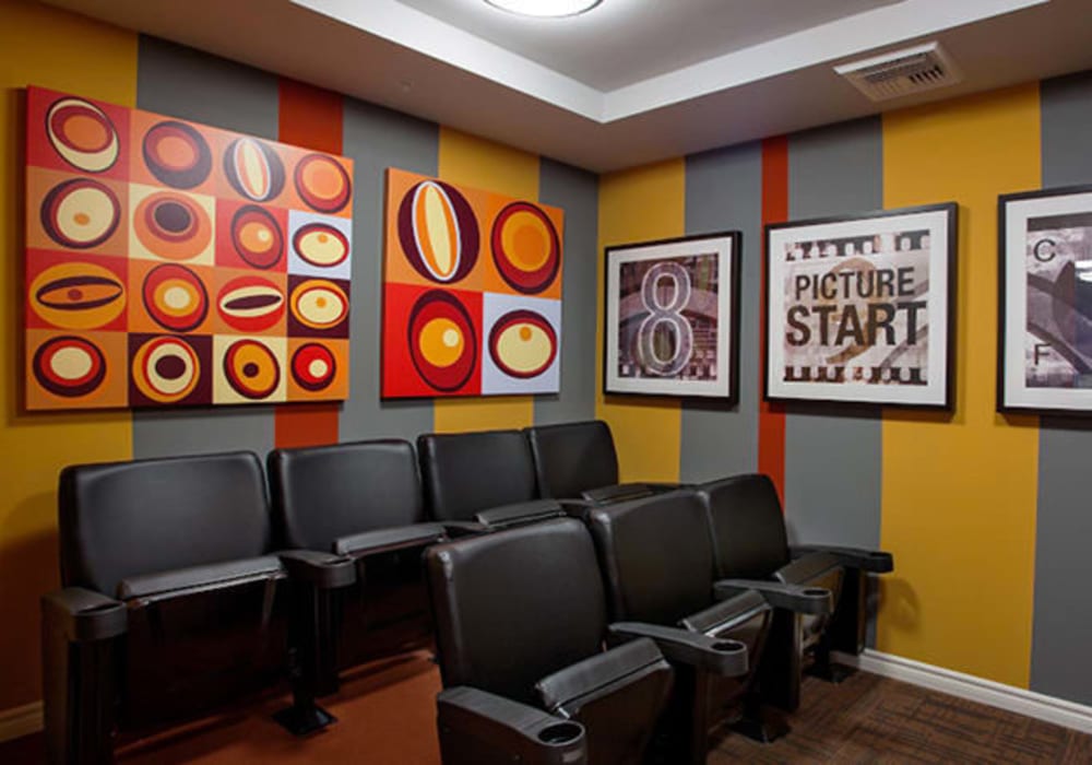 Theatre room with posters and comfortable chairs at Mercado Apartments in Perris, California