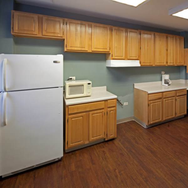 Kitchen with white appliances and wooden cabinets at The Caroline in New York, New York