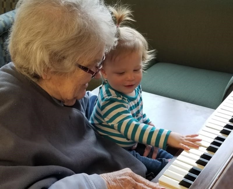 A resident shows her young visitor how to play a piano at Ebenezer Ridges Campus in Burnsville, Minnesota