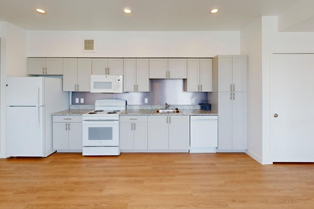 Cozy apartment kitchen with wood-style flooring & energy-efficient appliances at The Rose on Colfax in Denver,Colorado