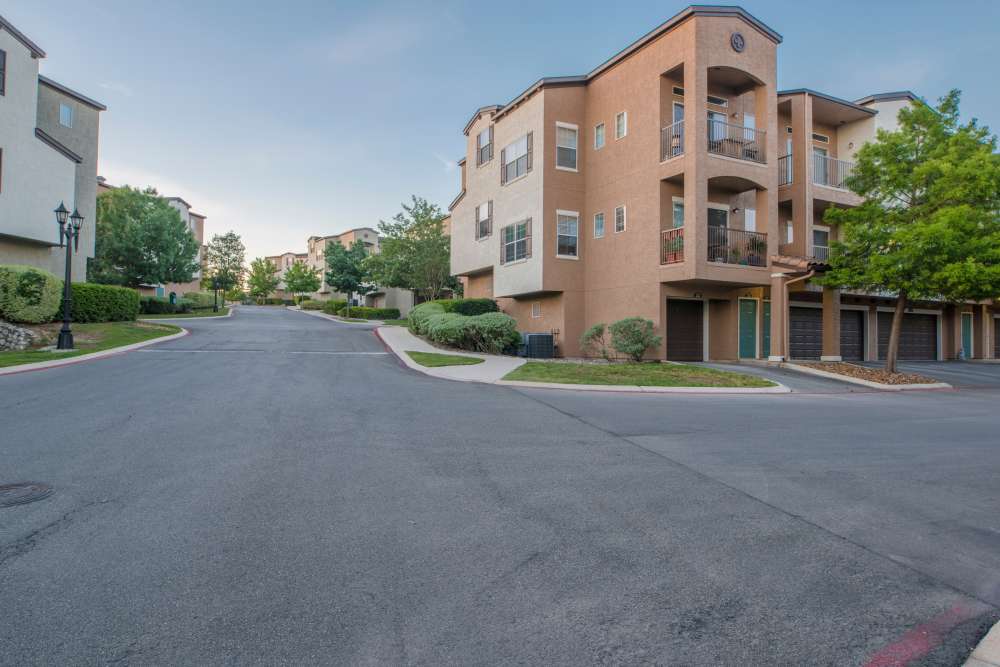 View of exterior of apartments and green lawn at The Abbey at Stone Oak in San Antonio, Texas