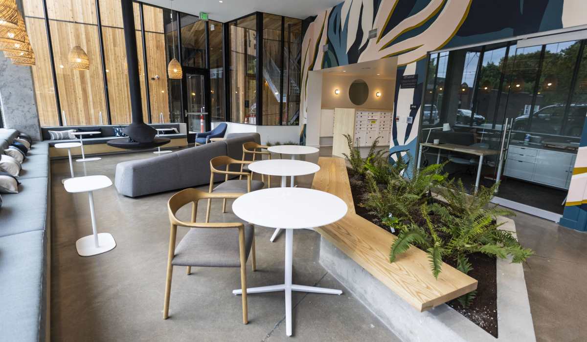 Modern resident lounge with floor-to-ceiling windows and seating at Brookland Apartments in Portland, Oregon