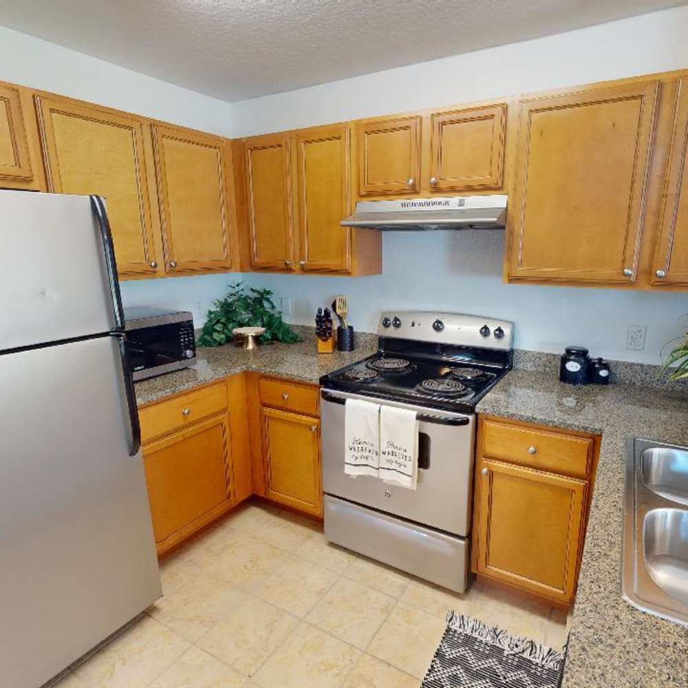 Bright kitchen with granite countertops, stainless steel appliances, and wooden cabinets at The Reserve at Brookhaven in Palm Coast, Florida