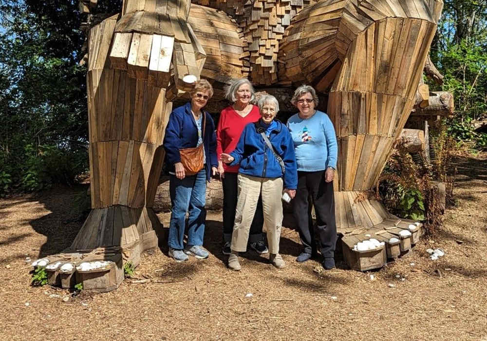 Resident posing in front of a wooden troll statue near Merrill Gardens at Tacoma in Tacoma, Washington