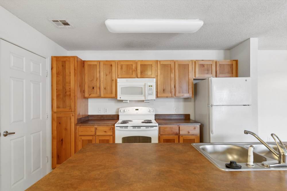 Charming kitchen showcasing warm wood cabinetry and modern appliances at Covington Woods Apartments in Lansing, Kansas.