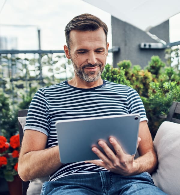 A resident relaxing on a seat outside with a tablet at Foundry Yards in Birmingham, Alabama