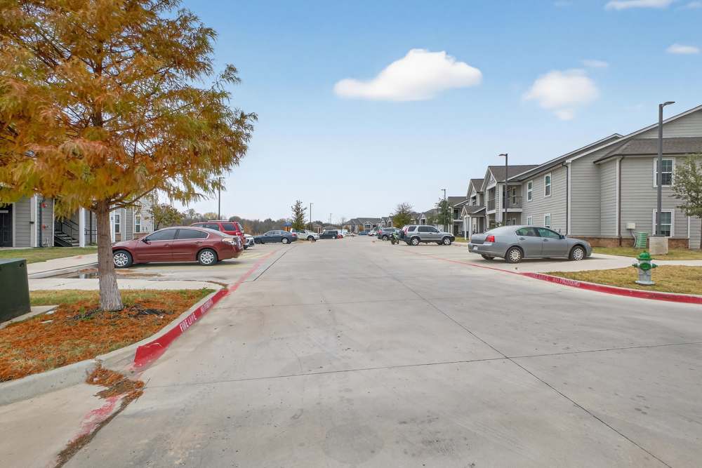 Charming neighborhood streets lined with lush landscaping and modern apartments at Lakewood Crossing in Granbury, Texas.