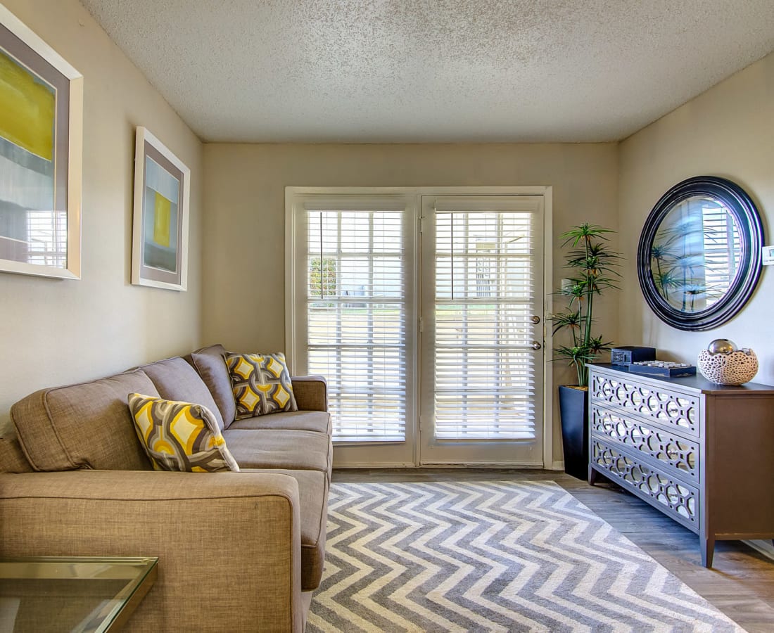 A living room with doors leading out to a private balcony at Canyon Grove in Grand Prairie, Texas