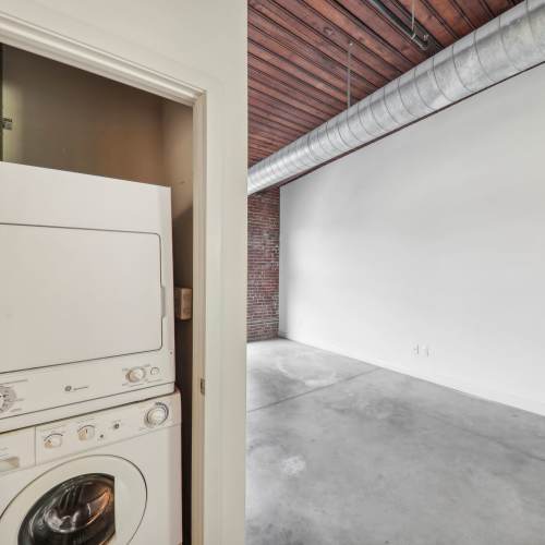 Laundry room with stackable washer and dryer at Stadium Loft Apartments in Saint Louis, Missouri