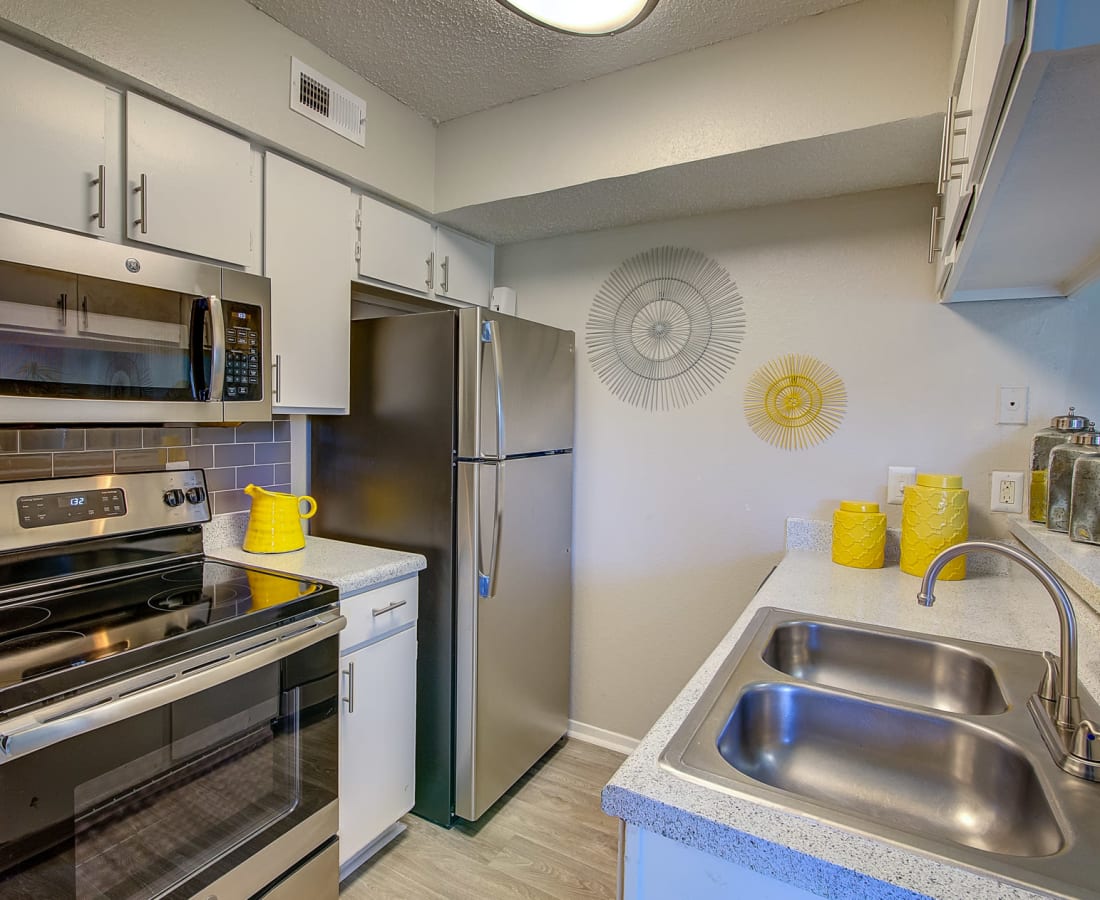 A modern kitchen with stainless-steel appliances and a tile backsplash at Canyon Grove in Grand Prairie, Texas