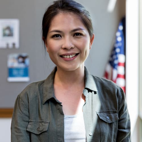 A resident smiling and standing in front of a flag in an office near Bayview Hills in San Diego, California