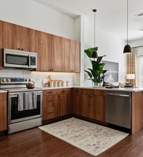 Modern kitchen with stainless-steel appliances and quartz countertops in a model apartment at 4600 Ross in Dallas, Texas