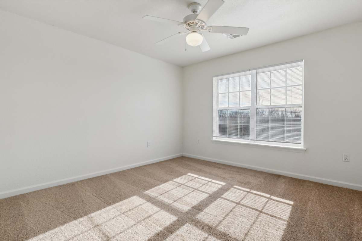 Bedroom with ceiling fan and carpet flooring at Nottingham Village in Gardner, Kansas