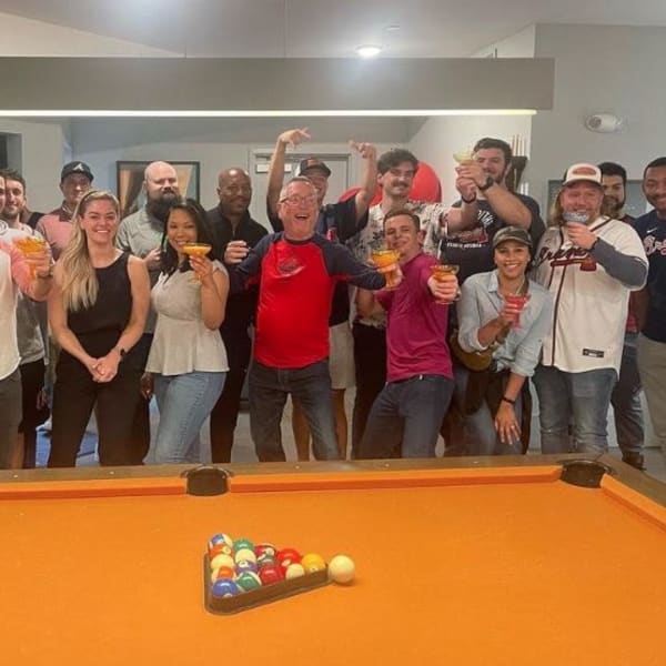 Group of people posing for a picture around the pool table at Revel Ballpark in Smyrna