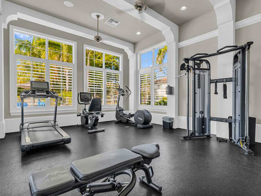 Bright fitness center with cardio machines and weight equipment, large windows, and natural light at Amberton Luxury Townhomes in Naples, Florida
