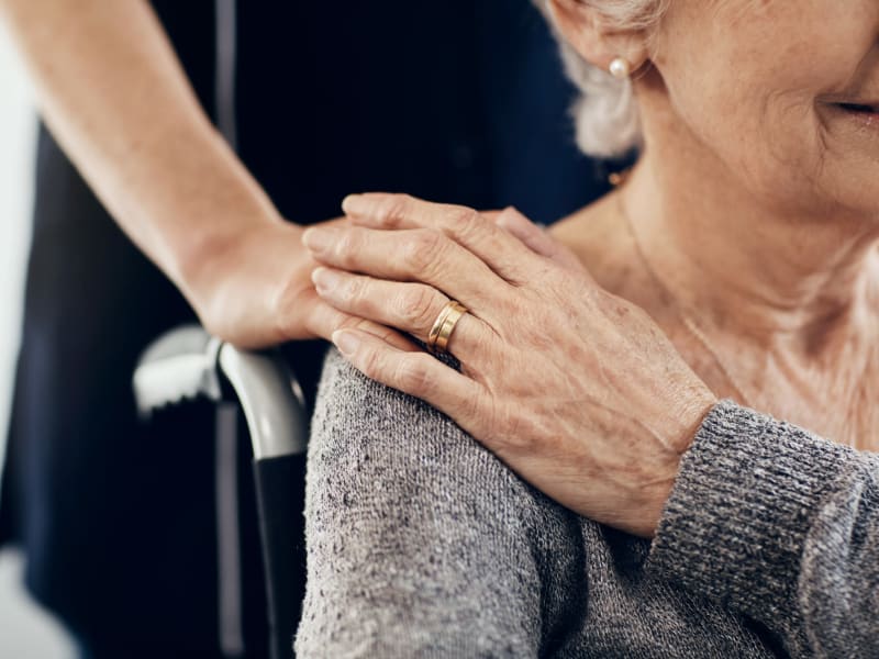 Caretaker holding the hand of a resident in hospice care at Holton Manor in Elkhorn, Wisconsin