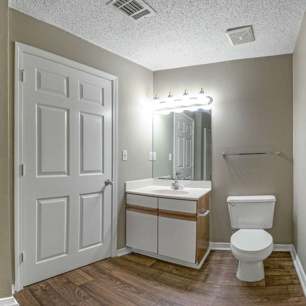 Bathroom with a mirror, white vanity unit and wood-style flooring at Royal Gulf Apartments in Biloxi,Mississippi