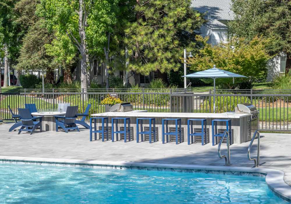 Firepit and grill area beside a swimming pool at Cotton Wood Apartments in Dublin, California