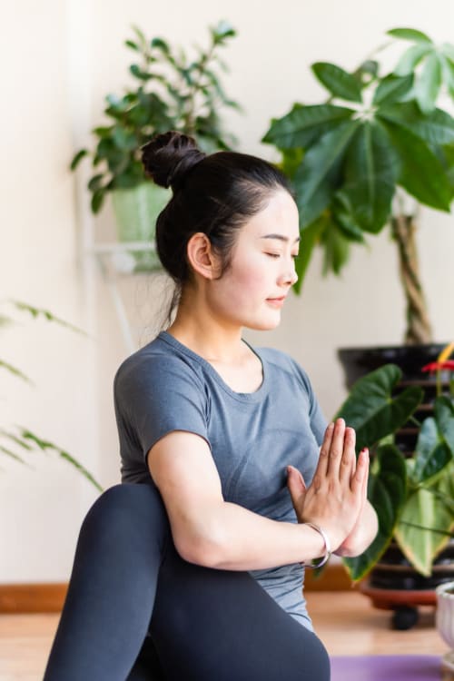 Woman practicing yoga with some lovely plants behind her at The Cambridge Apartments in Washington, District of Columbia