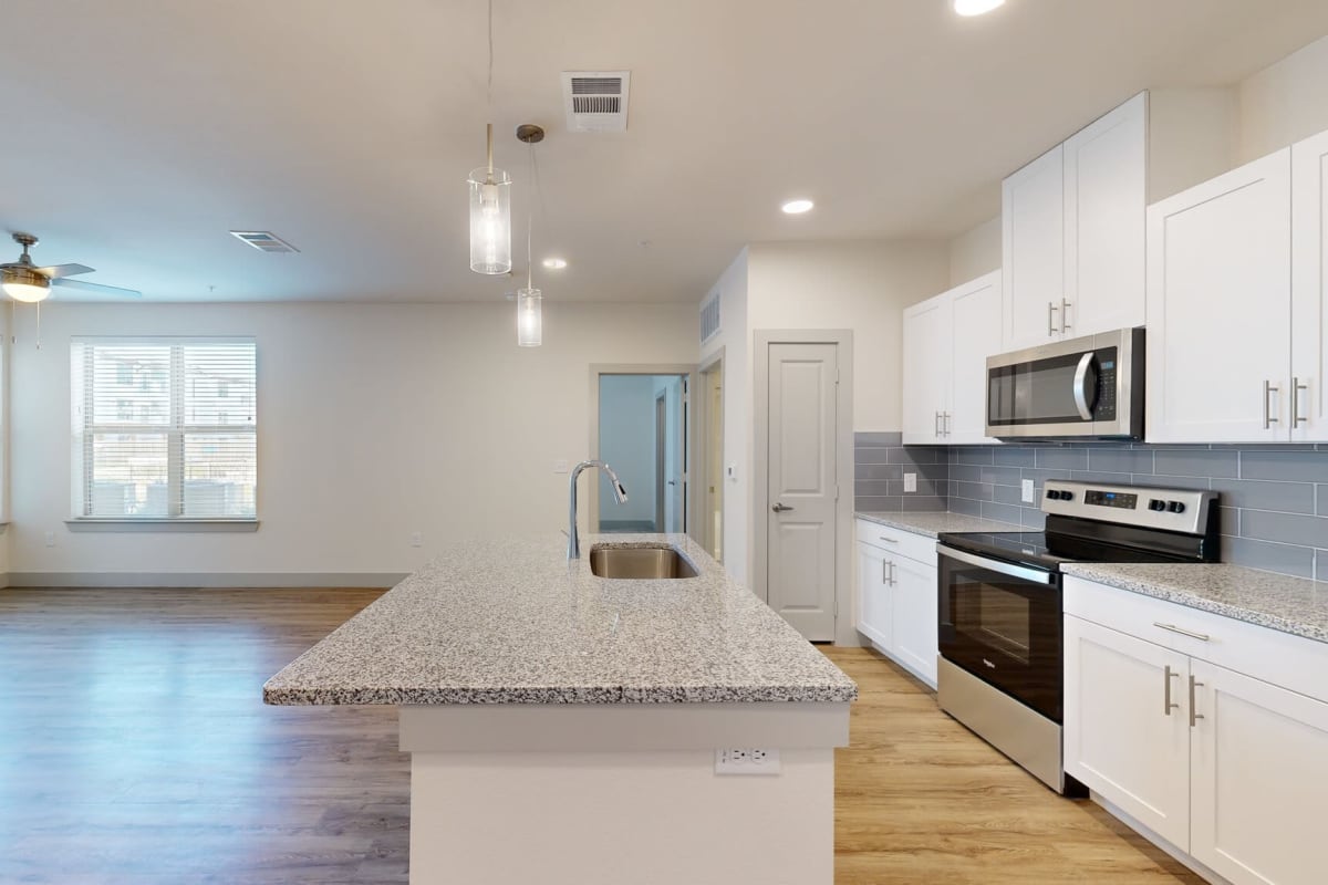 Kitchen with a tile backsplash at The Grand At Saginaw in Saginaw, Texas