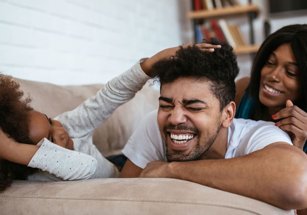 Family of a mother, father, and child playing in the living room together at Everwood at The Avenue in Murfreesboro, Tennessee