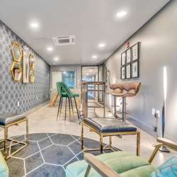 Seating area with green chairs and hexagonal rug at Latitude at South Portland in Portland, Maine