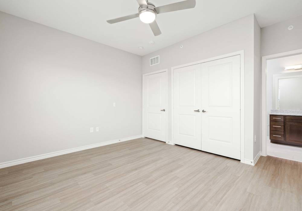 Modern bedroom with closet, ceiling fan and bathroom at Redwood in San Marcos, Texas
