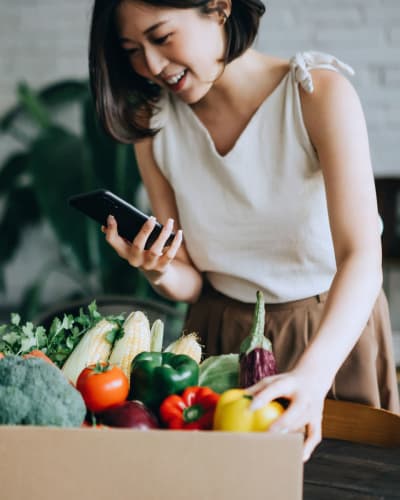 Resident returning home to her apartment with a box of fresh produce from a farmers market near Vantage Park Apartments in Seattle, Washington