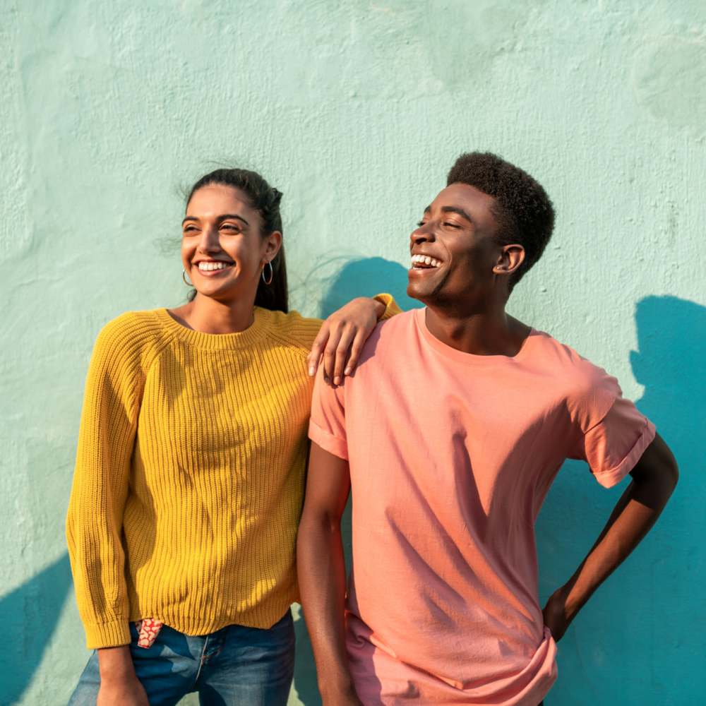Two smiling young adults standing together against a colorful wall, enjoying a sunny day at The Arcadia in Madison, Tennessee