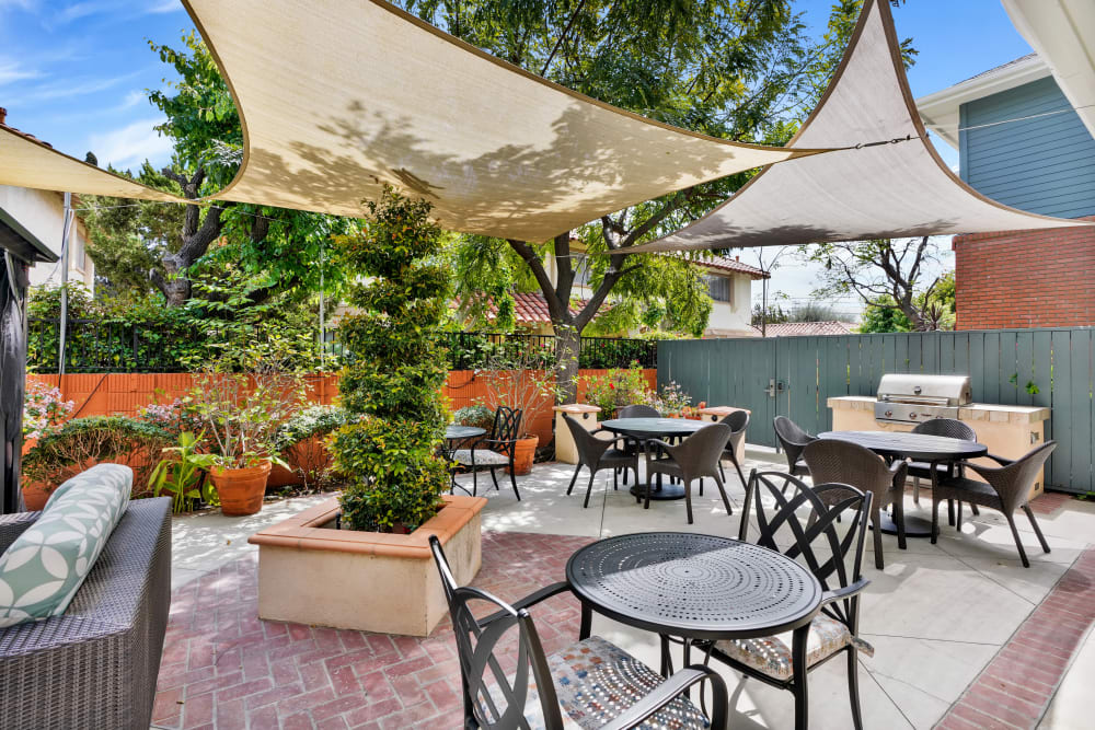 Outdoor dining and patio with tables, chairs, and sun shades at Kirkwood Orange in Orange, California