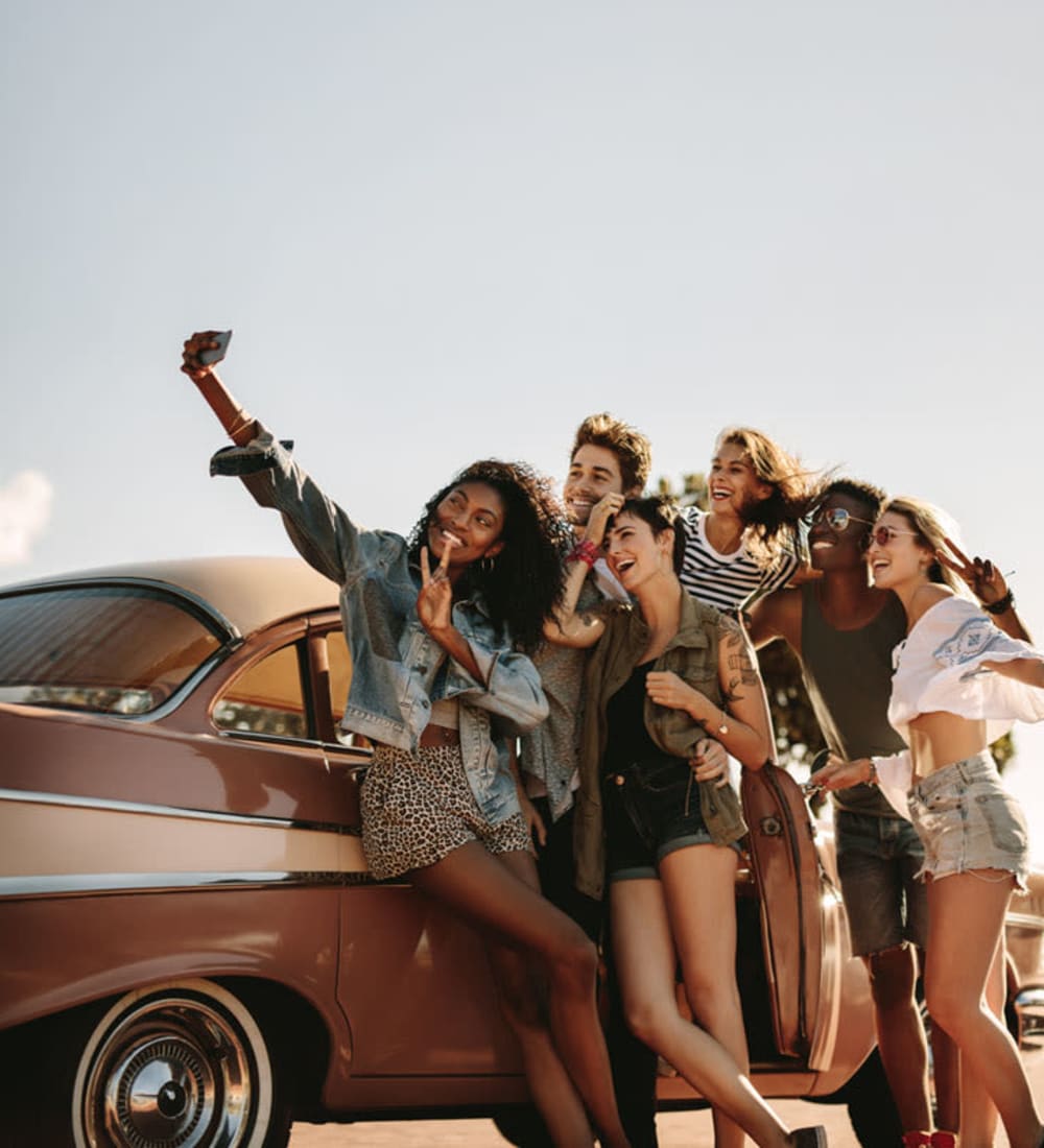 Student friends posing for a photo in front of a classic car near The George in Statesboro, Georgia