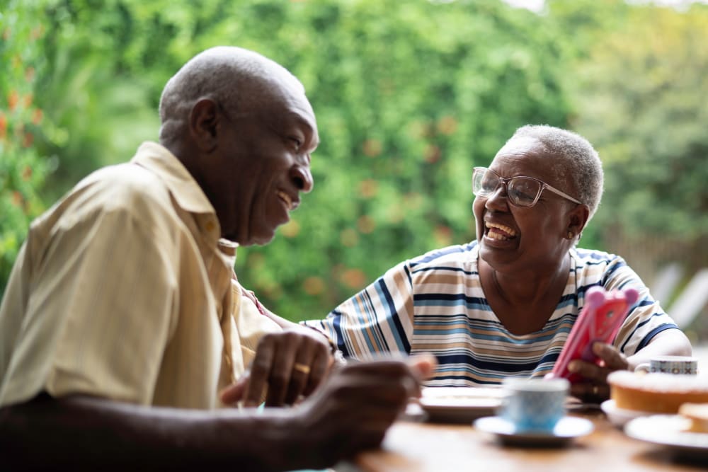 Resident couple laughing while looking at a mobile phone at Merrill Gardens at Sheldon Park in Eugene, Oregon. 