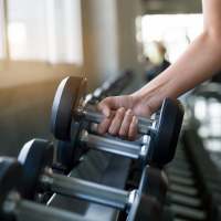 Resident working out with dumbbells in the fitness center at Compass Landing in Newport, North Carolina