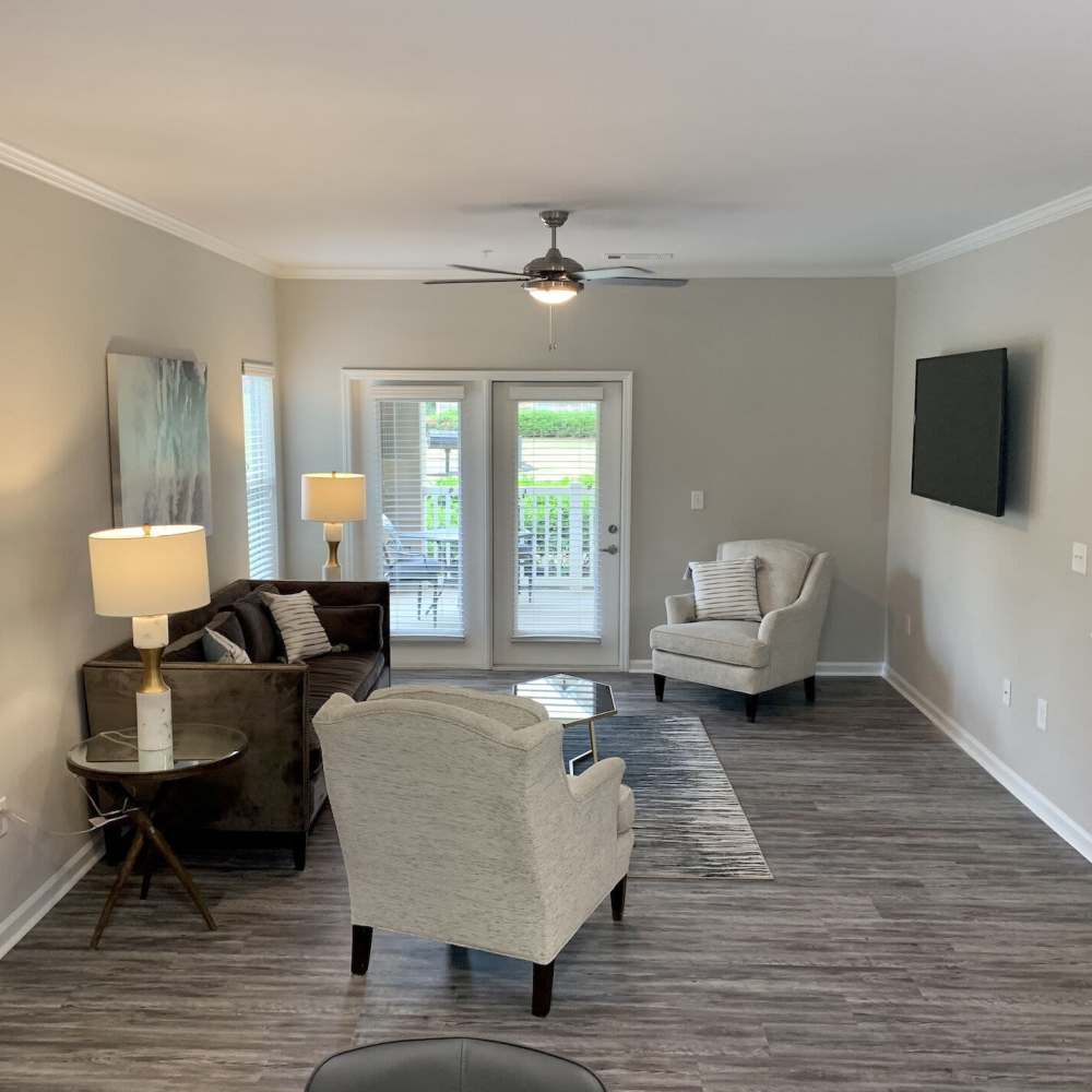 Living room with ceiling fan, television and doors leading to private balcony at Preserve At Columbus Park in Columbus, Georgia