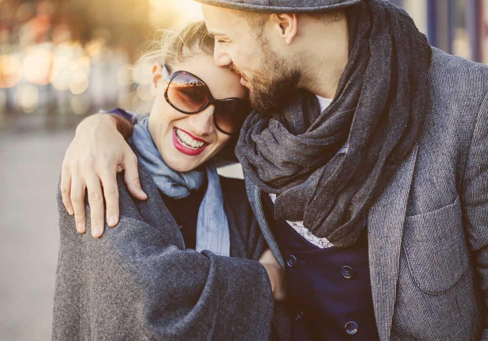 Resident couple hugging and laughing as they stroll through the neighborhood near Sofi Redwood Park in Redwood City, California